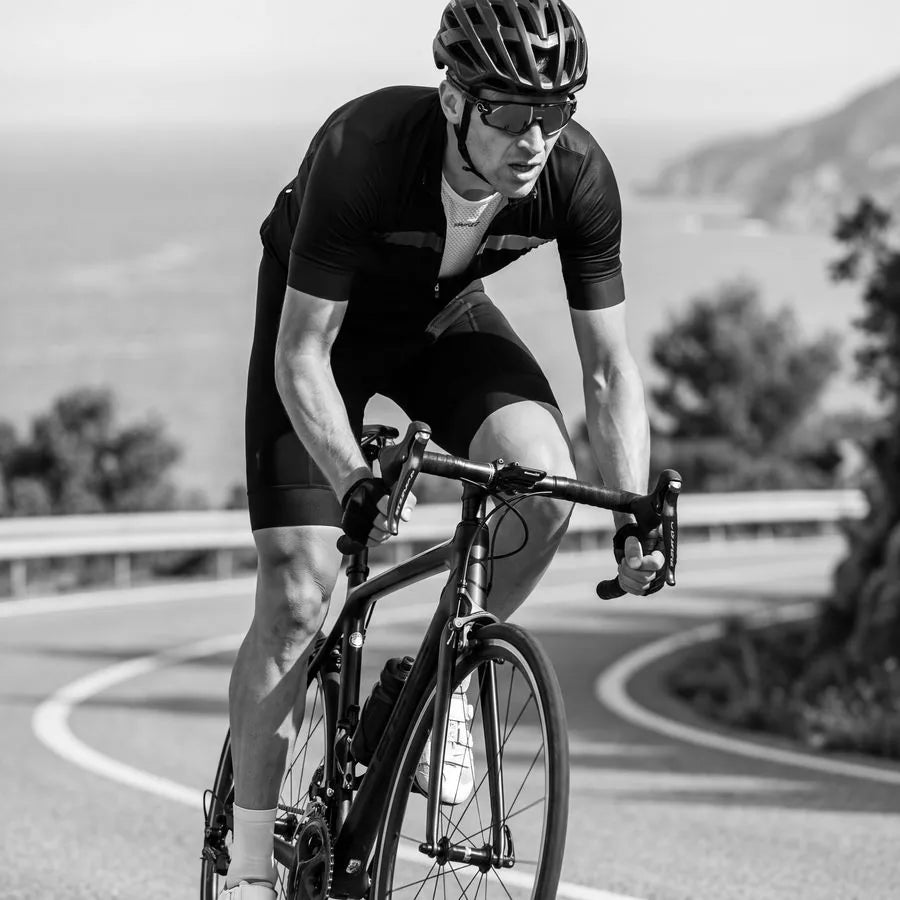 Cyclist riding a coastal road, black and white
